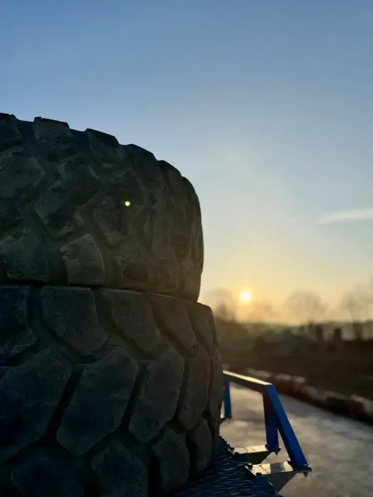 Großer LKW Reifen auf Transportfläche bei Sonnenuntergang für Reifenhandel, Export und professionelle Entsorgung
